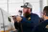 Aviation maintenance instructor using a pneumatic drill on an airplane.
