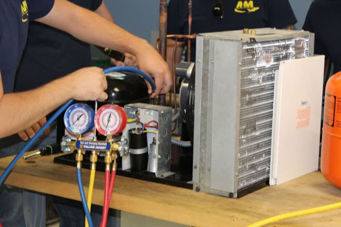 AIM HVAC students working on an air conditioner