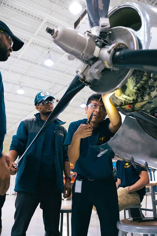 AIM students working on the engine of a small plane