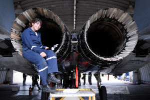 Aviation maintenance technician sitting next to an airplane engine