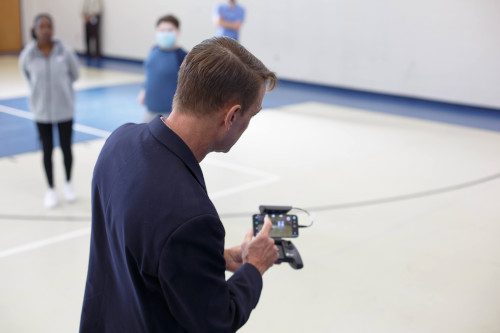 Drone instructor using a remote to control a drone.
