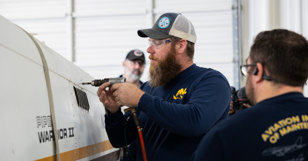 Aviation maintenance students practicing hands-on skills on an aircraft fuselage as part of the aviation maintenance curriculum at AIM.